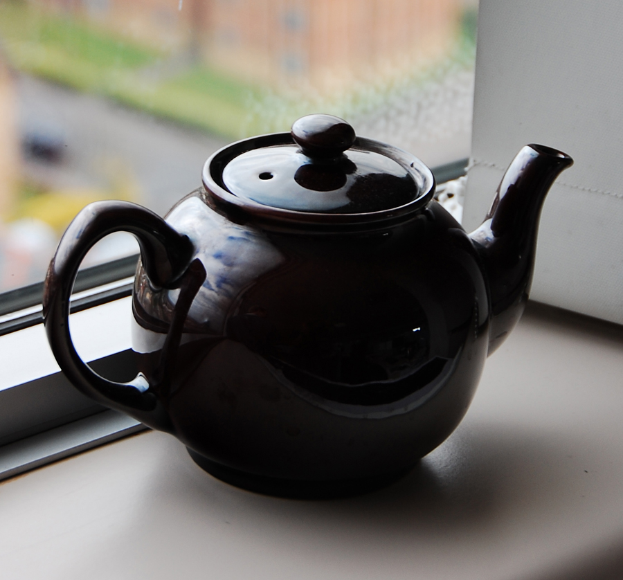 A black teapot on a windowsill